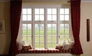 Large White timber casement window with cottage bars finished with a window seat from the Anglian double glazing range